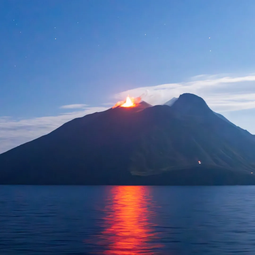 Nächtlicher Ausbruch des Stromboli, der sich im Meer spiegelt
